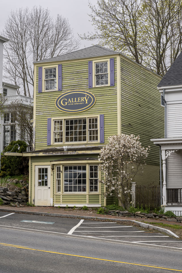 A green multi-story building has the sign Gallery one eleven on it.
