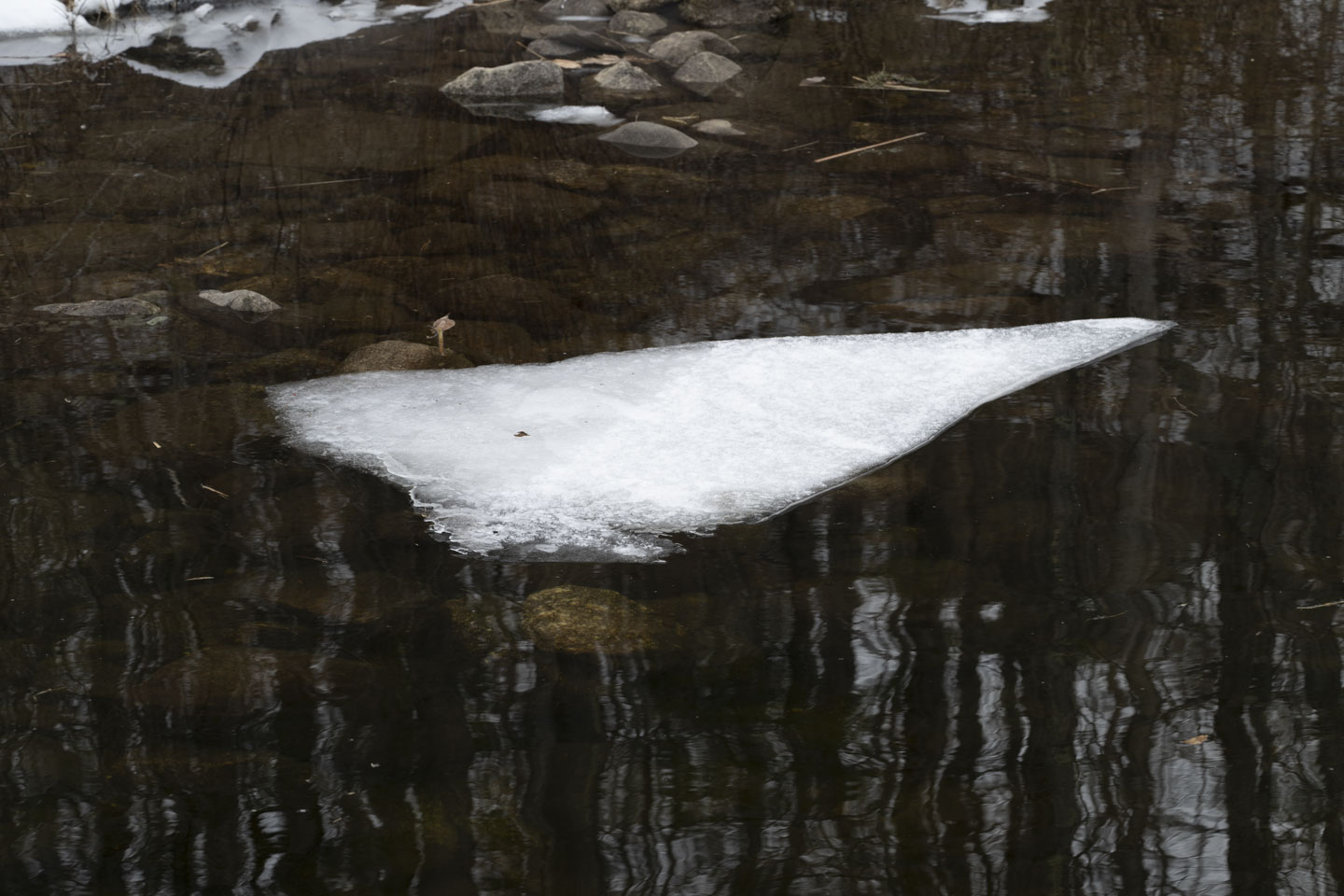 A triangular piece of ice floats in water.
