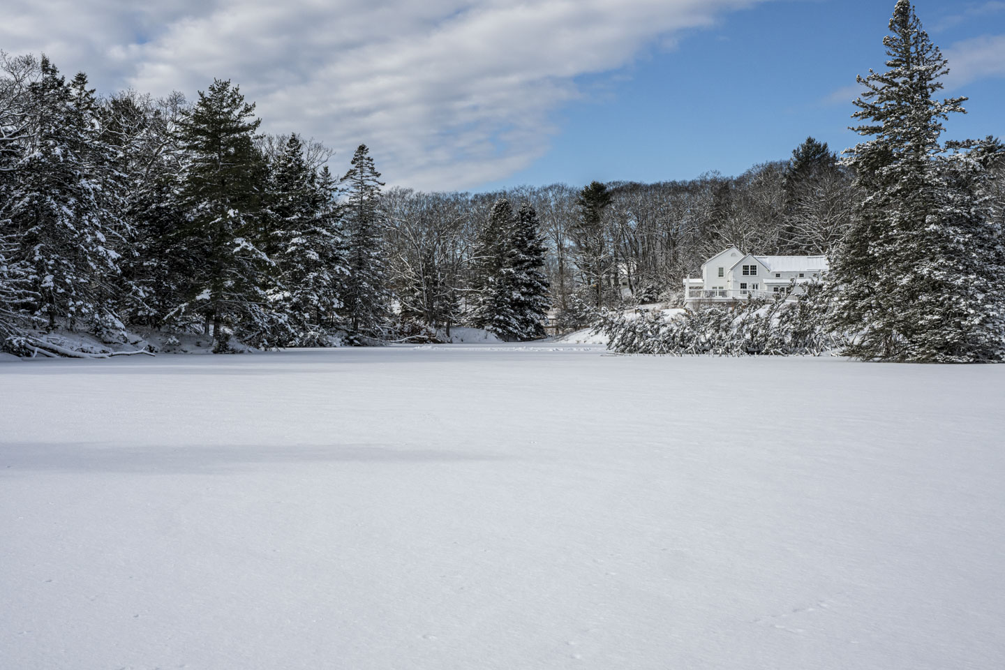 The sun is shining on a frozen snow-covered pond.