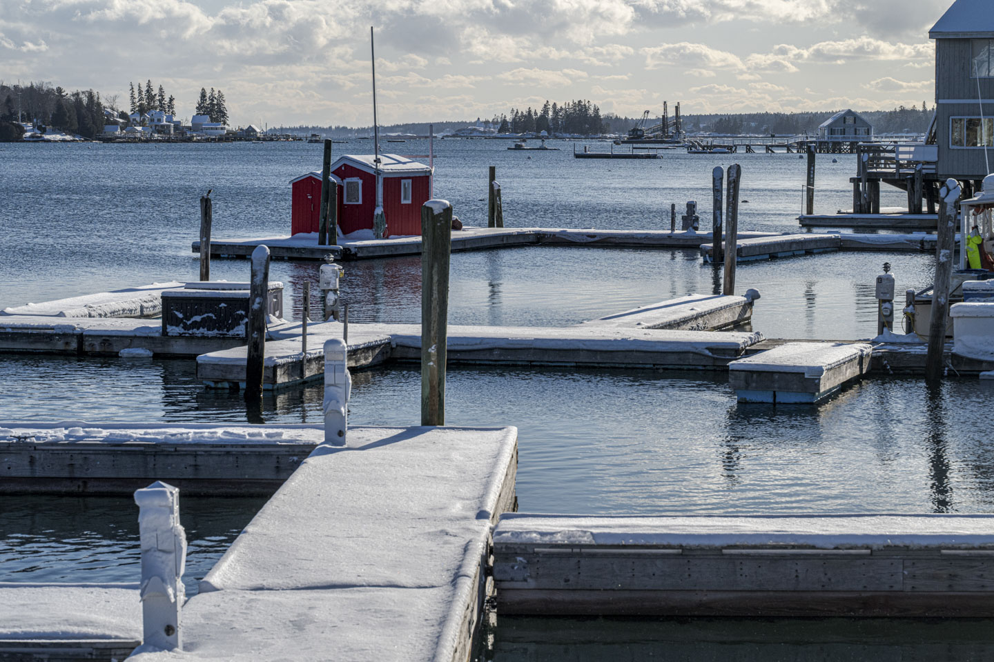 A red shed is on a floating dock. Everything has a bit of snow on it.