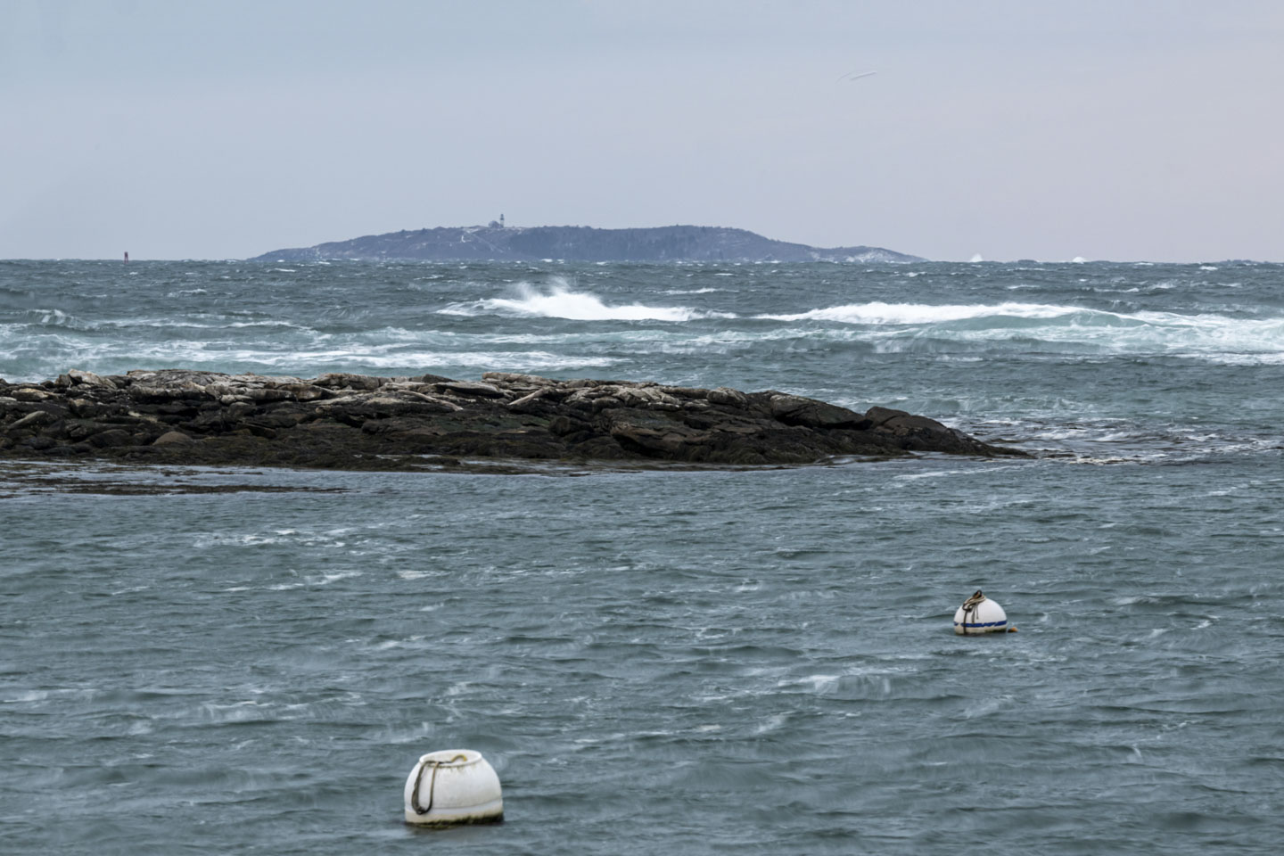 This is a closer view of the Seguin lighthouse, with rough water and a couple of buoys in the foreground.