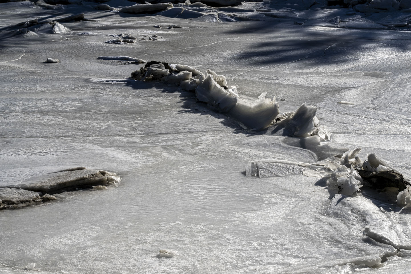 A ridge of ice is broken over some rocks.