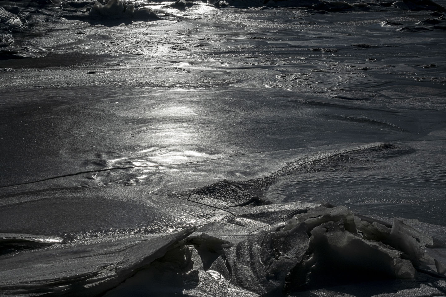 The bright sun is shining on ice, making the rest of the photograph dark.