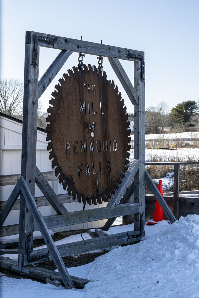 A large old round saw blade is hanging as a sign that says The Mill at Pemaquid Falls.