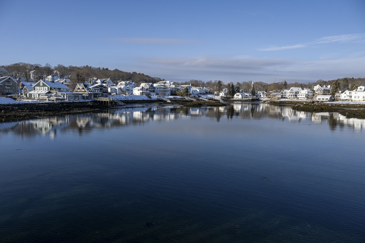 A sunny day makes it easy to see houses that line the water edge and are reflected in it.