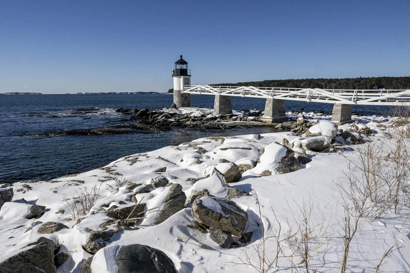 Marshall Point Lighthouse is seen with snow on the rocks.