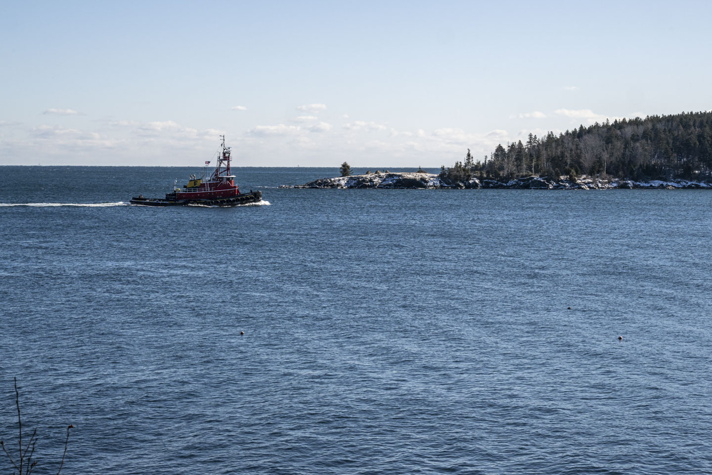 The tugboat Fournier Girls is approaching a channel between the mainland and an island.