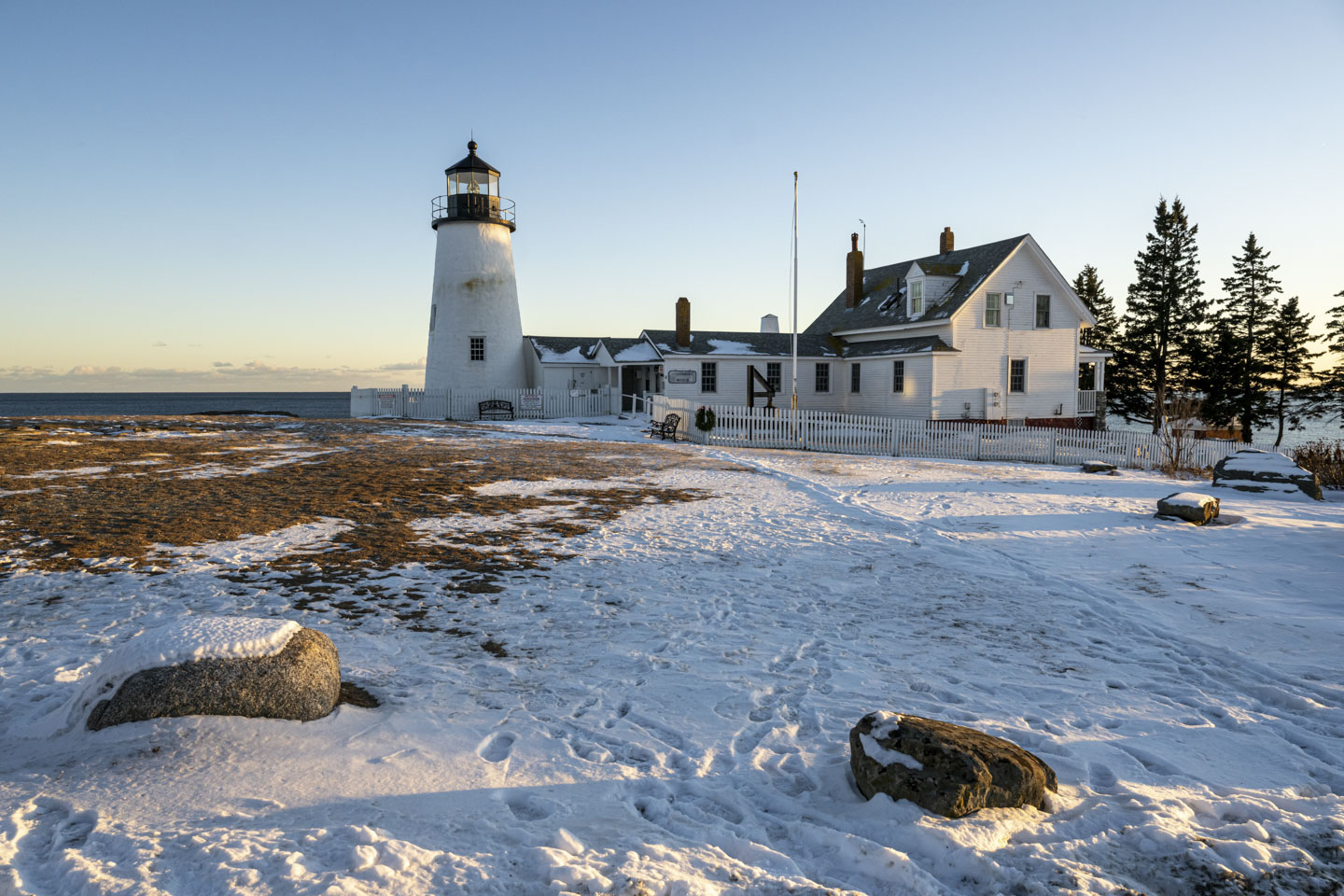 Pemaquid lighthouse has a partially snow-covered yard.