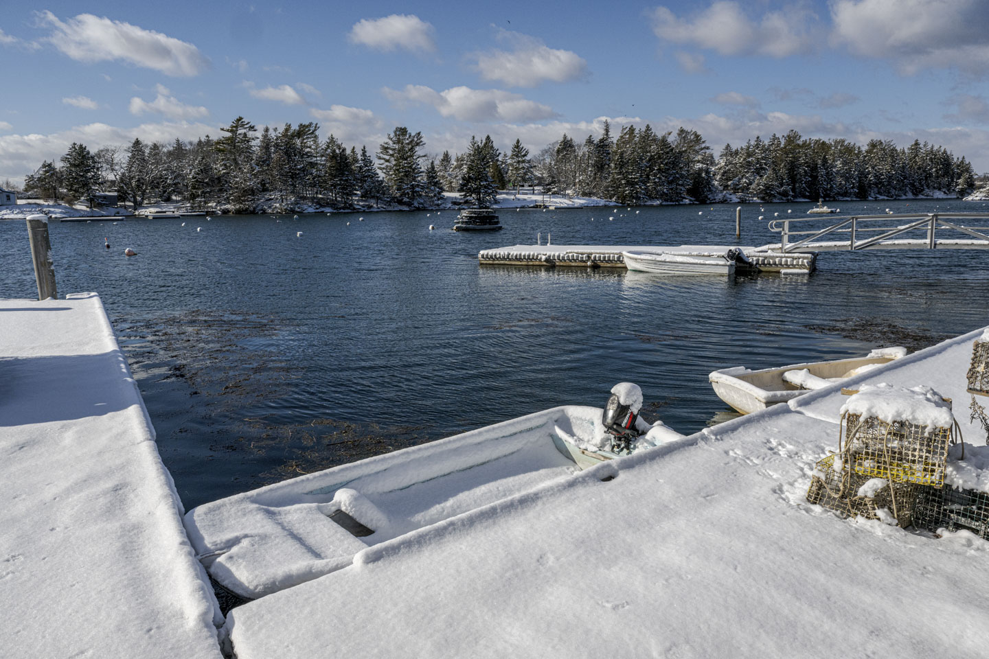 A view of the snow-covered dock, and a small skiff that also has snow on it.