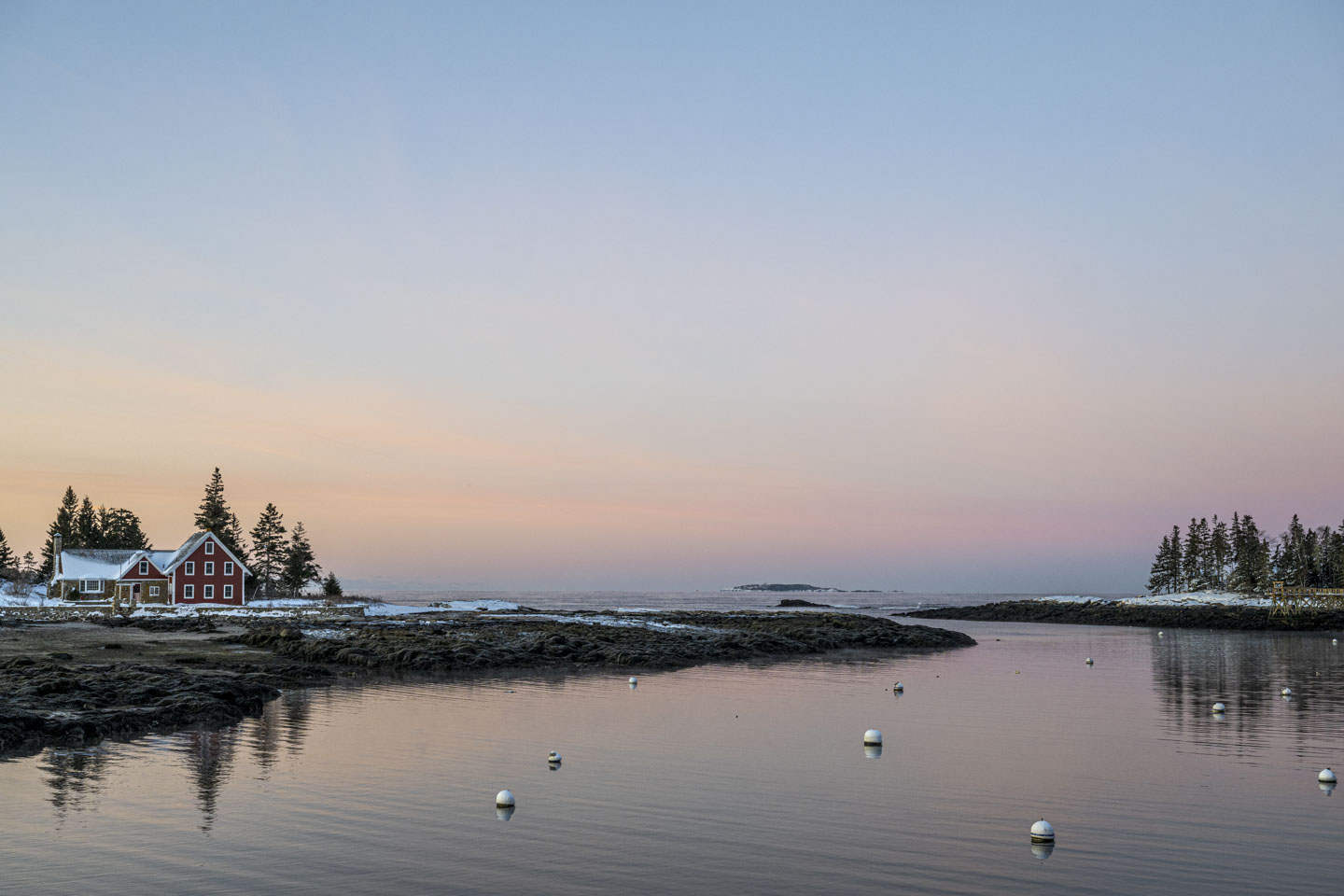 The red house is on the left and the small island is on the right. In the distance Seguin can be seen. The sky is pink and azure.