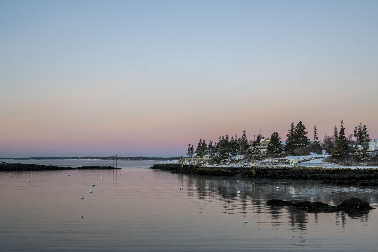 Snow covers the ground on the right, while in the middle of the picture are buoys in water.