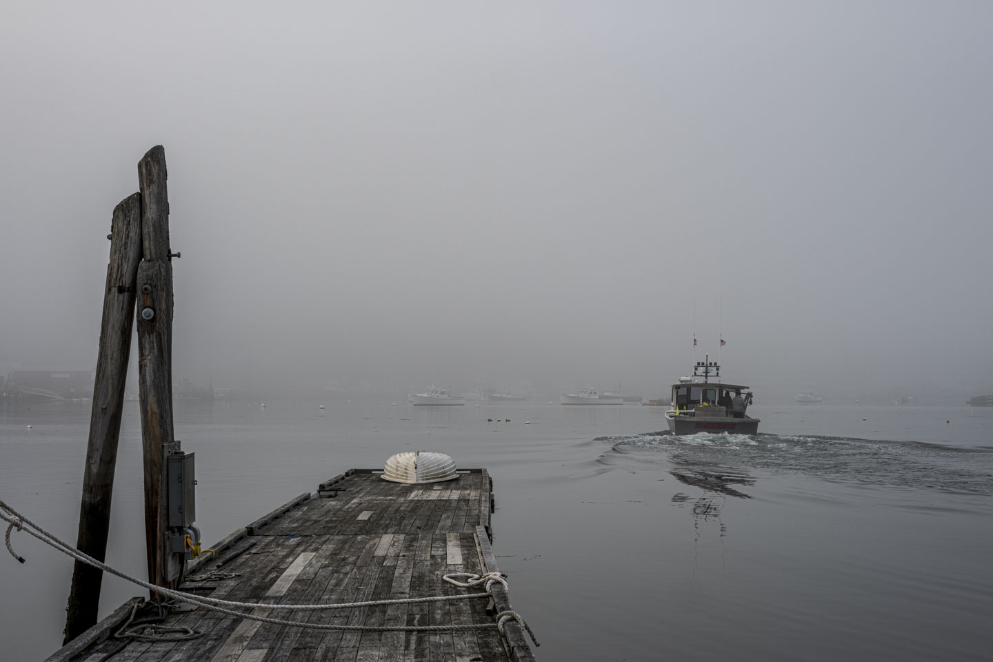 A boat leaves a pier and goes into the fog.