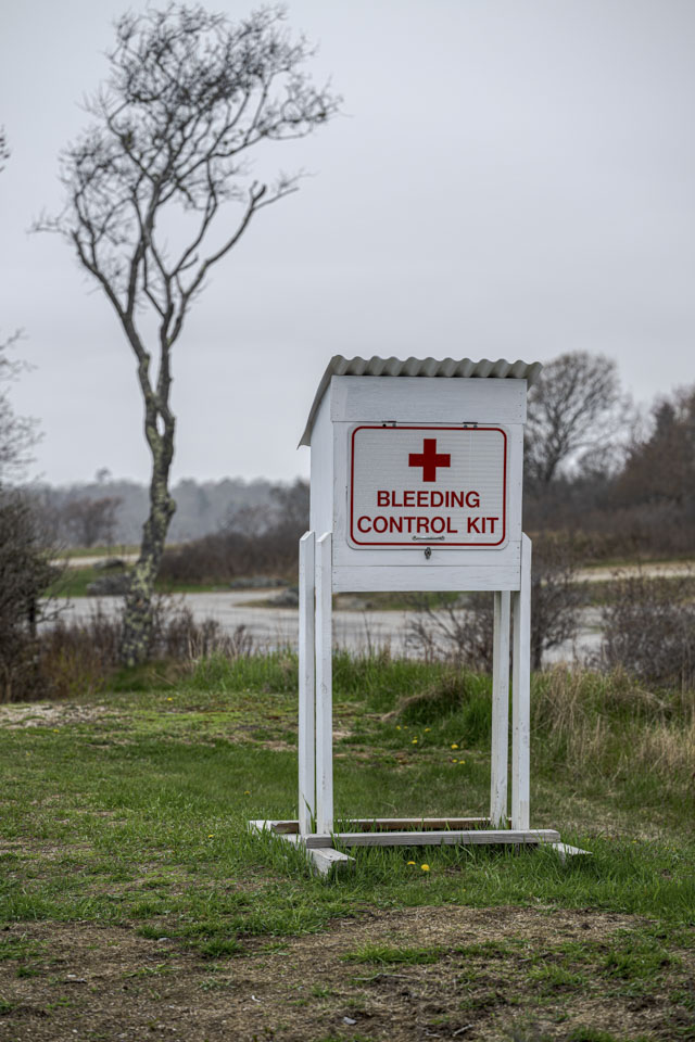 A white case with the words Bleeding Control Kit is on a stand on grass.