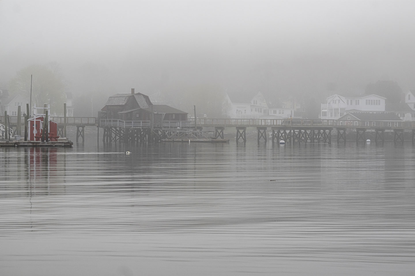Through fog, the footbridge, bridgehouse, and red shed can be seen.