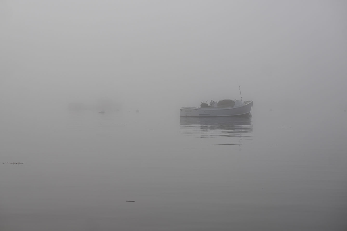 A closer view of the same boat as in the previous picture shows the dim outline of another boat or raft beyond it.