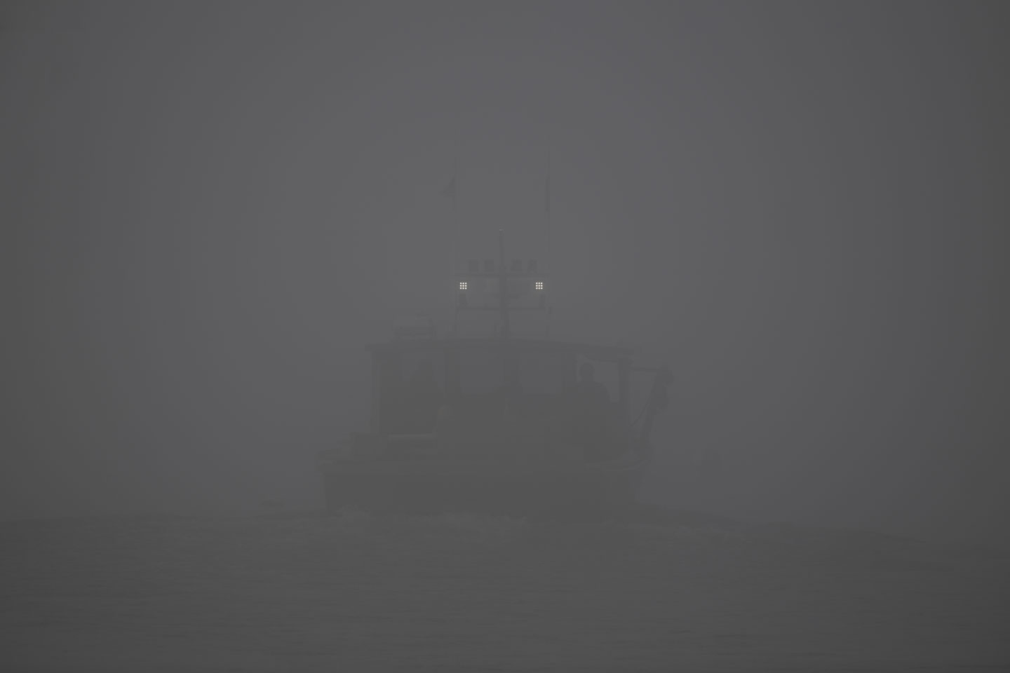 The lights of a boat can be seen through the fog.