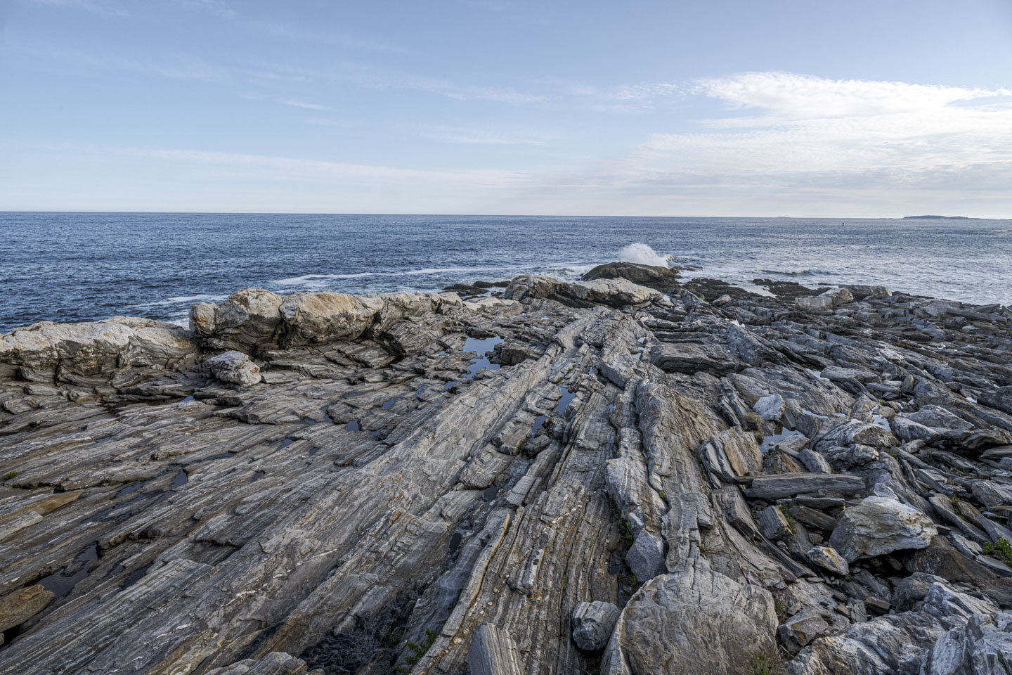 The rocks have very distinct lines that run towards the ocean.