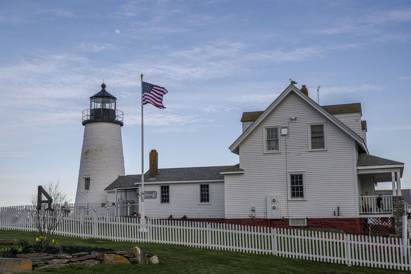 The moon is visible above the lighthouse.