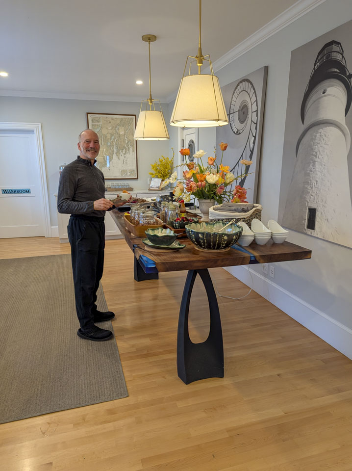 Paul is standing next to a tall table that has food and flowers on it.
