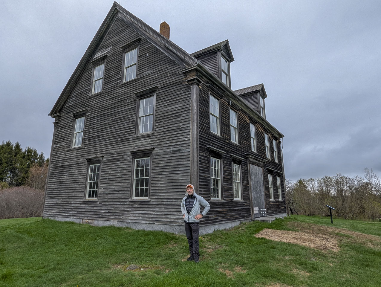 Paul is standing in front of the corner of the brown Olson House.