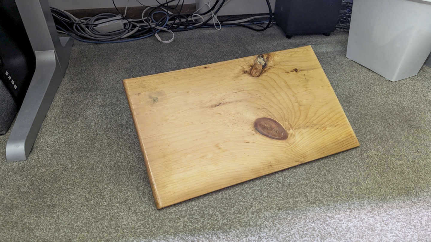 Finished rectangular wooden footstool resting on the carpet beneath a desk