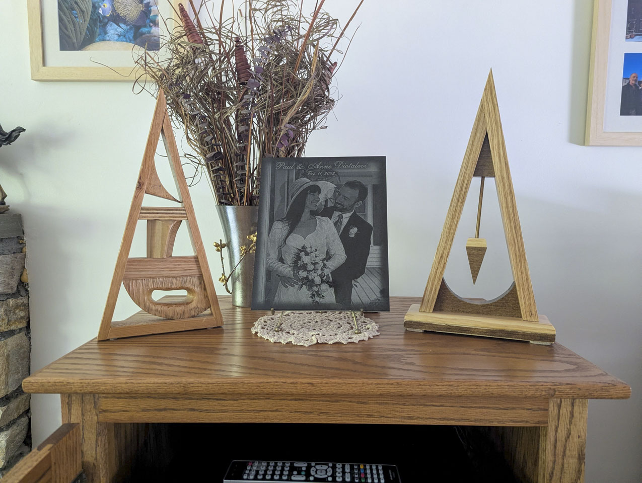 Two triangular wooden sculptures displayed on either side of a framed wedding photograph