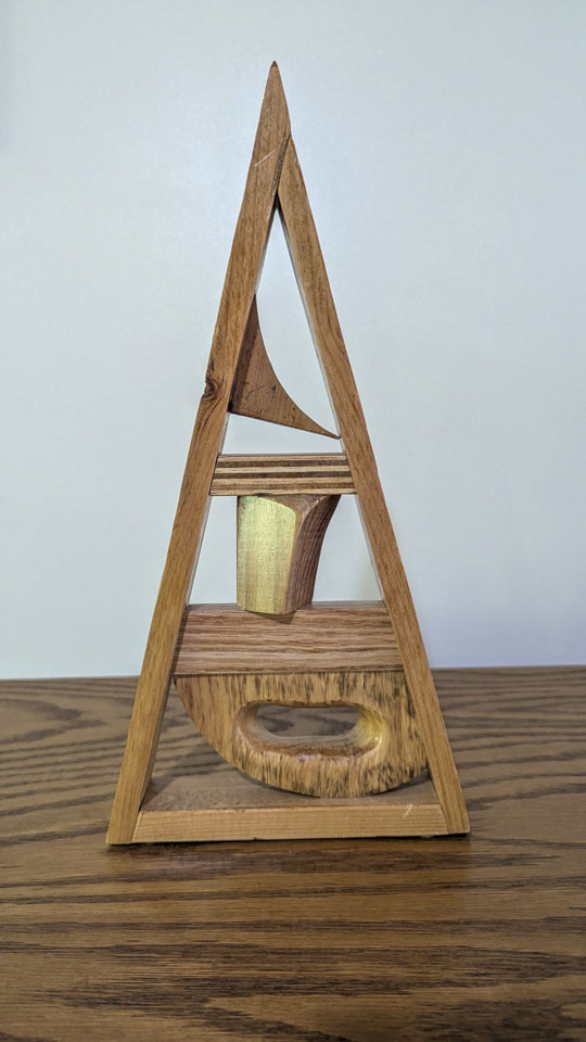 Triangular wooden sculpture with curved and geometric pieces arranged inside the frame