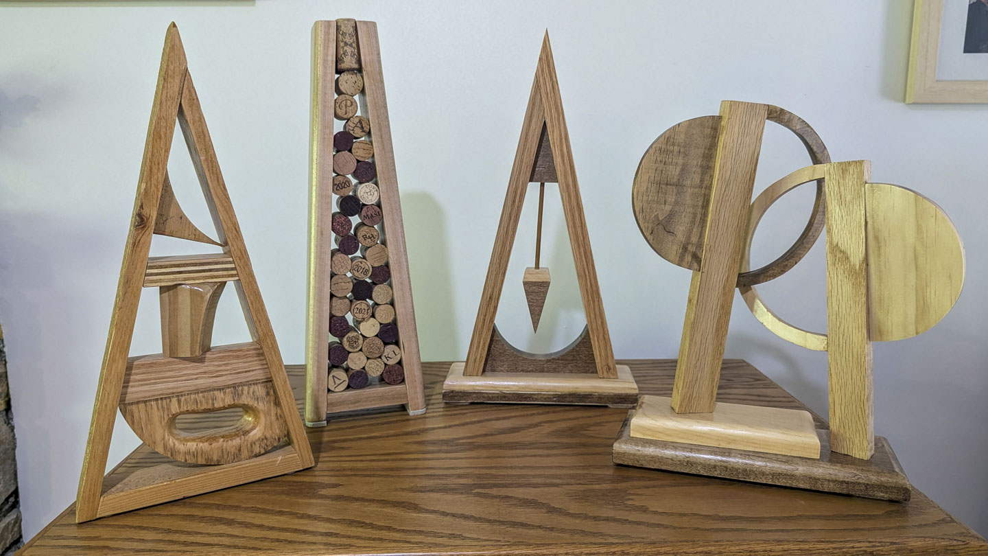 Four handmade wooden sculptures displayed together on a wooden cabinet
