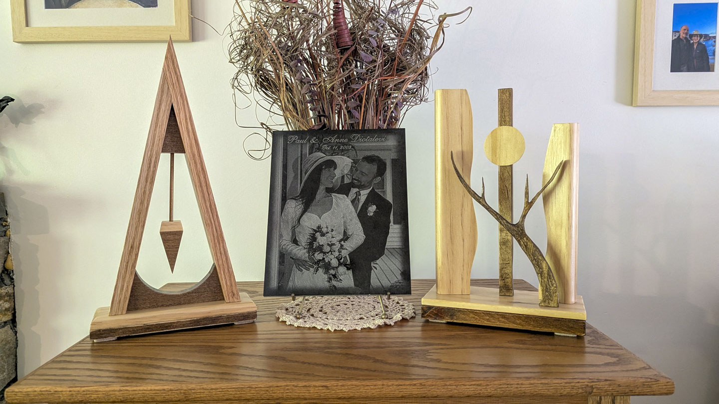 Two handmade wooden sculptures displayed on either side of a framed wedding photograph.