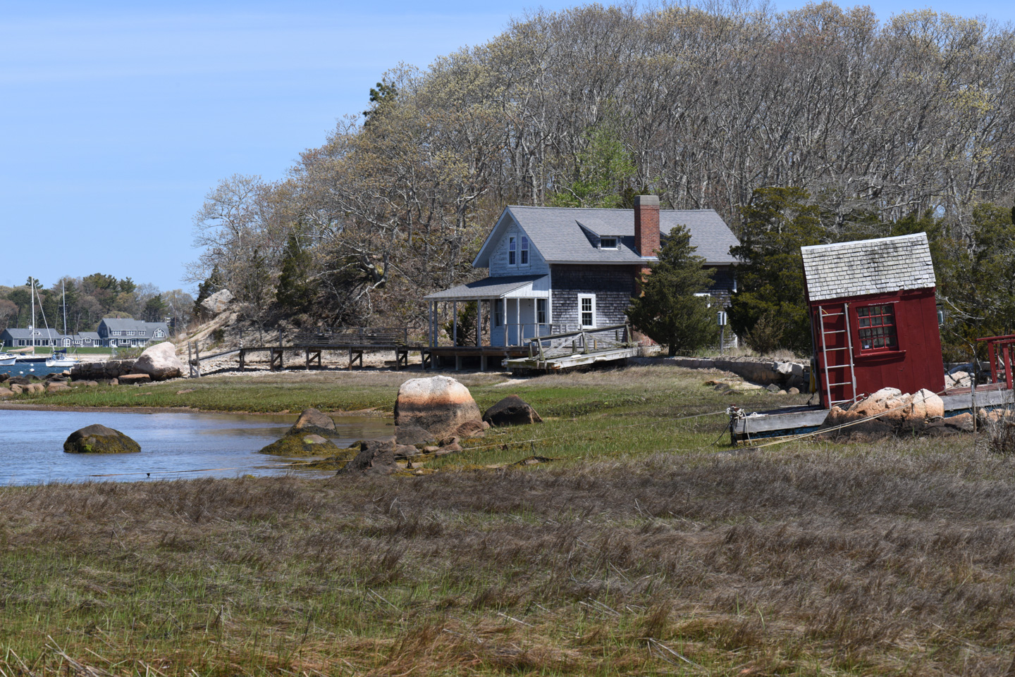 A waterfront house with a red shed on a grounded float