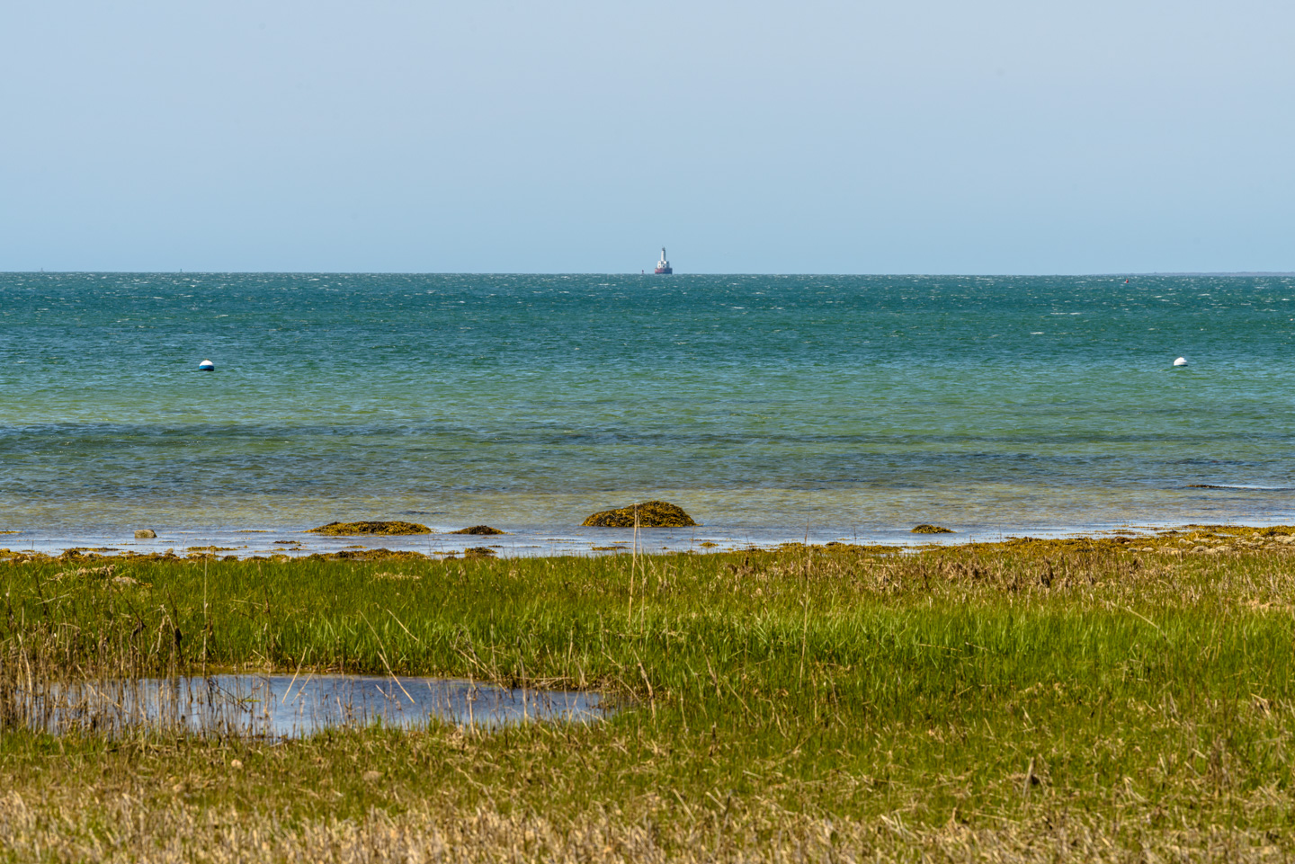 View out across the water with a lighthouse just showing in the distance