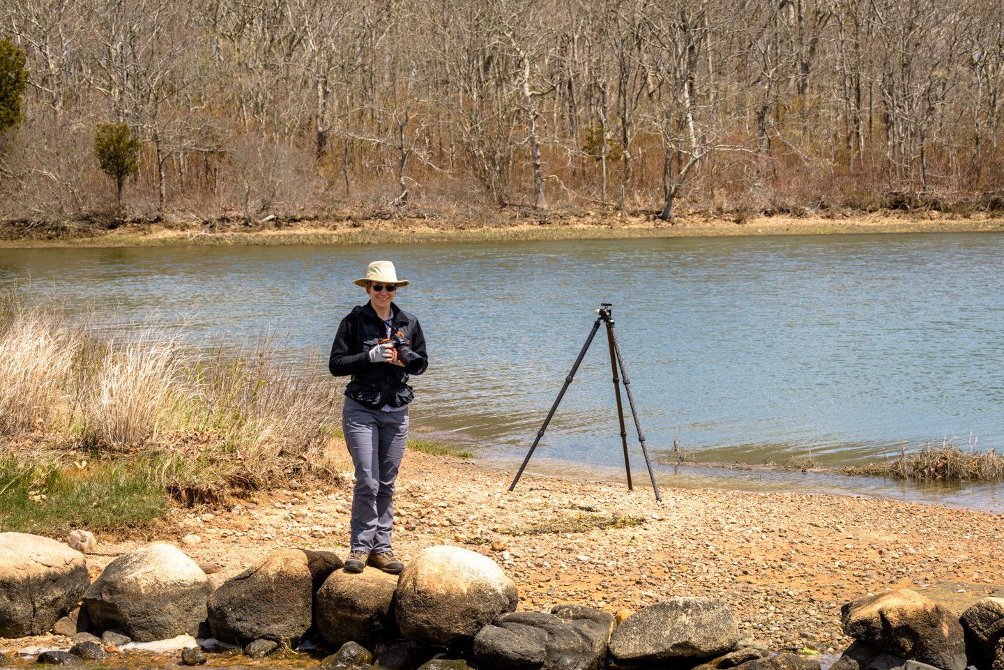 Anne on the beach area of the Lloyd Center, wearing a sun hat and photography vest while carrying her camera