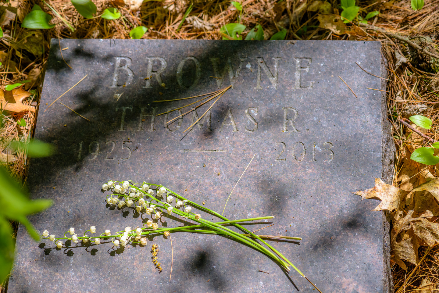 Cemetery marker with Lily of the Valley flowers lying on it