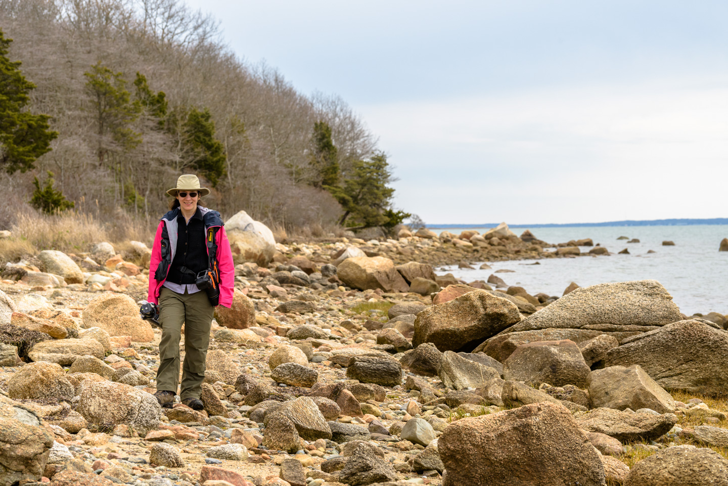Anne on the beach carrying camera and tripod